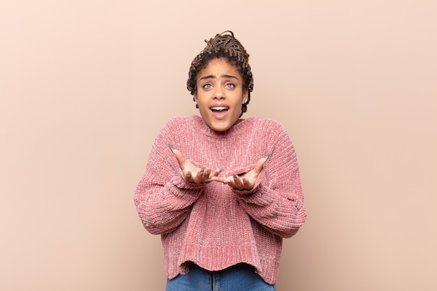 Junge Afro-Frau, die stolz, positiv und lässig aussieht und mit beiden Händen auf die Brust zeigt