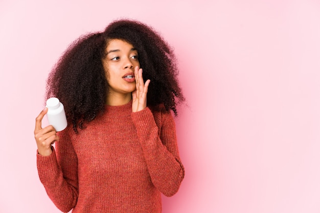 Junge Afro-Frau, die Vitamine hält Junge Afro-Frau, die ein Vitaminglas hält