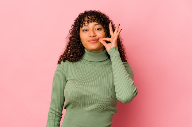 Junge Afro-Frau isoliert mit den Fingern auf den Lippen, die ein Geheimnis halten