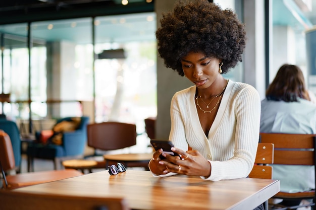 Junge Afro-Frau mit Handy im Café