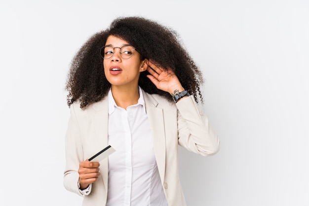 Junge Afro-Geschäftsfrau, die ein Gutschriftauto lokalisiert hält Junge Afro-Geschäftsfrau, die eine Gutschrift cartrying zum Hören eines Klatsches hält.