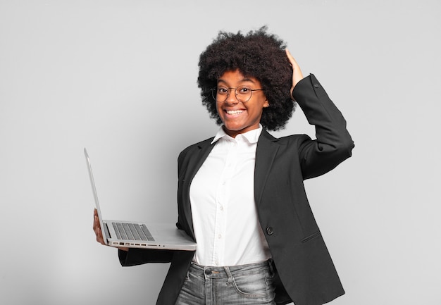 Junge Afro-Geschäftsfrau, die sich gestresst, besorgt, ängstlich oder verängstigt fühlt, mit Händen auf dem Kopf, die bei einem Fehler in Panik geraten.