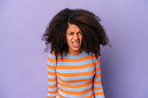 Foto junge afroamerikaner lockige frau isoliert auf lila wand schreien sehr wütend, wut konzept, frustriert.