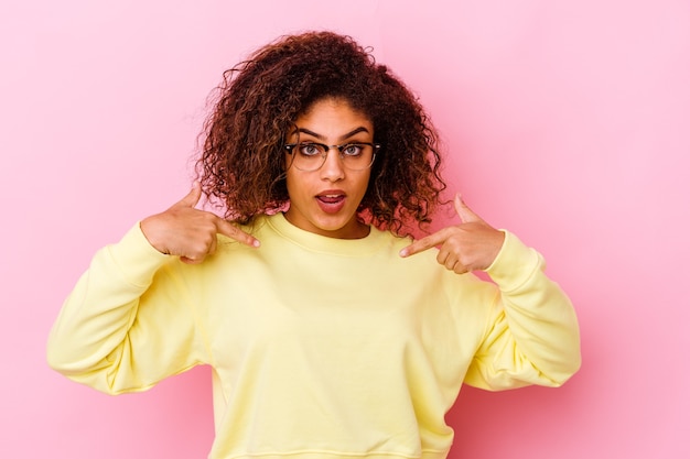 Junge Afroamerikanerfrau auf rosa zeigt nach unten mit den Fingern, positives Gefühl.