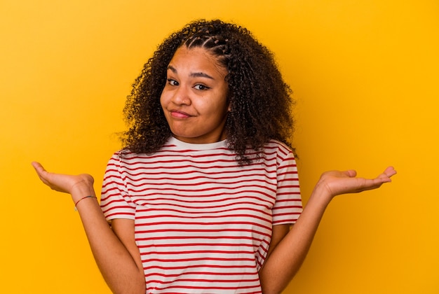 Junge Afroamerikanerfrau, die an den Schultern in der fragenden Geste zweifelt und zuckt.