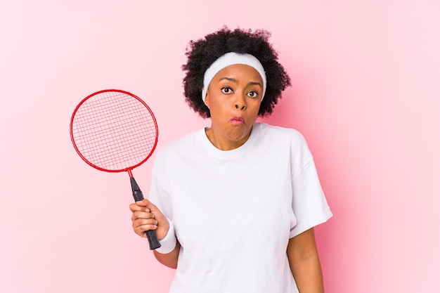 Junge Afroamerikanerfrau, die Badminton spielt, zuckte isoliert mit den Schultern und offenen Augen verwirrt.