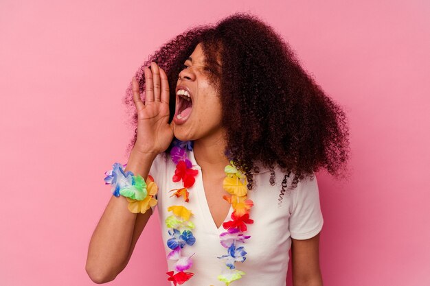 Junge Afroamerikanerfrau, die ein hawaiianisches Zeug trägt, das Handfläche nahe geöffnetem Mund schreit und hält.