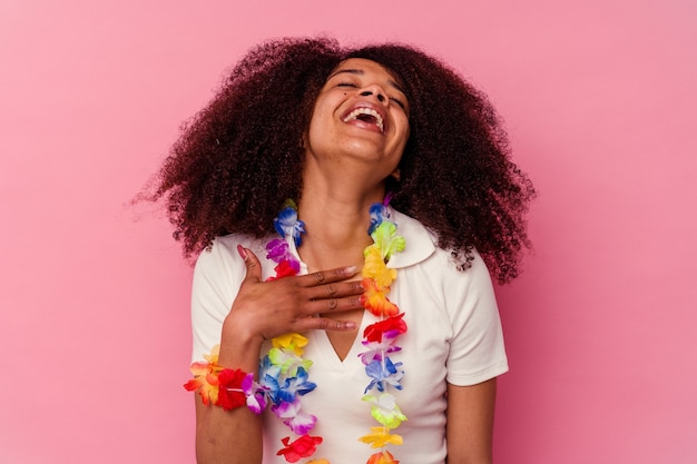 Junge Afroamerikanerfrau, die ein hawaiianisches Zeug trägt, lacht laut und hält Hand auf Brust.