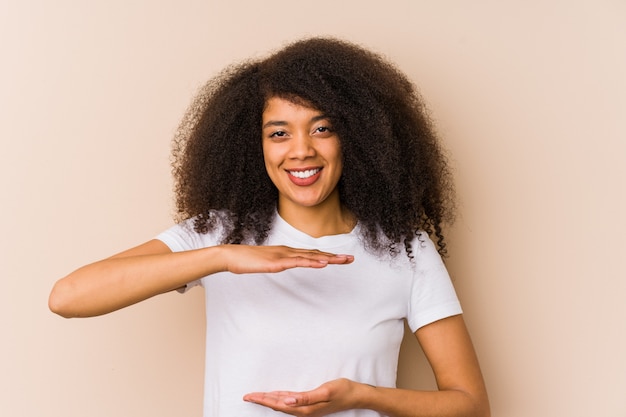 Junge Afroamerikanerfrau, die etwas mit beiden Händen, Produktdarstellung hält.