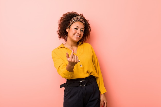 Junge Afroamerikanerfrau, die mit dem Finger auf Sie zeigt, als ob Einladung näher kommen.