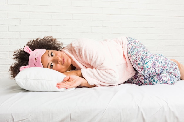 Junge Afroamerikanerfrau, die mit einem Kissen auf dem Bett schläft