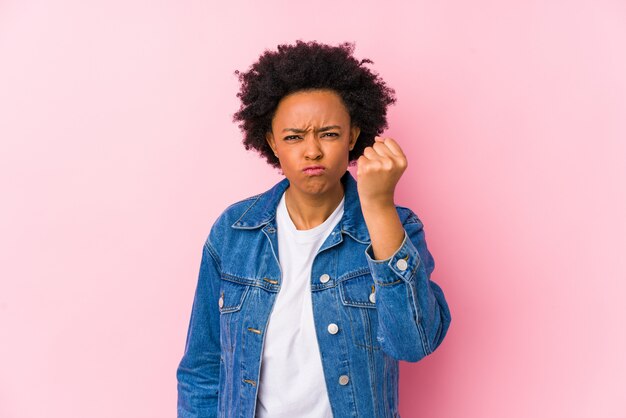 Junge Afroamerikanerfrau gegen eine rosa Wand, die Faust zeigt