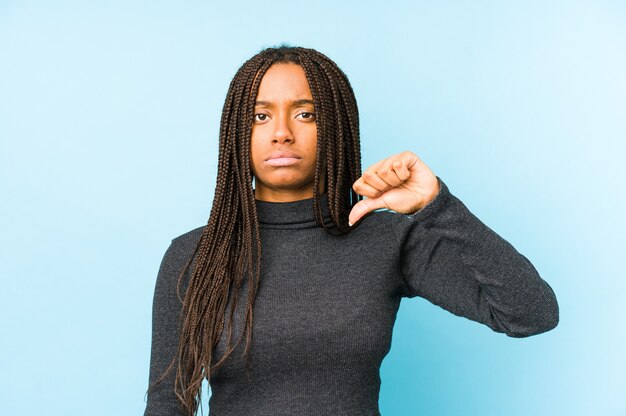 Junge Afroamerikanerfrau lokalisiert auf blauem Hintergrund, der eine Abneigungsgeste zeigt, Daumen nach unten. Uneinigkeit Konzept.