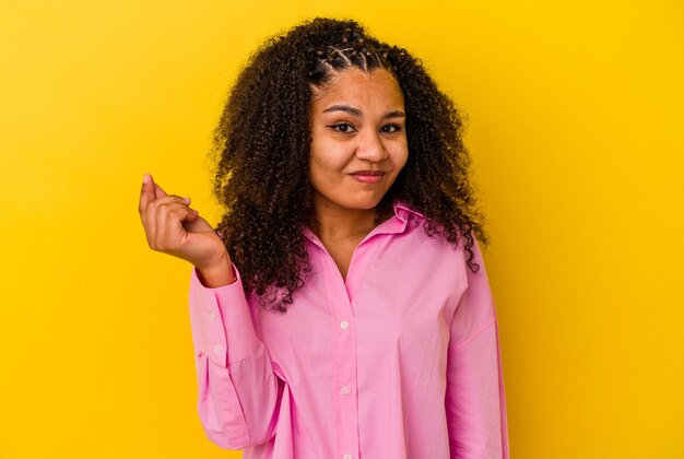 Junge Afroamerikanerfrau lokalisiert auf gelbem Hintergrund, der zeigt, dass sie kein Geld hat.