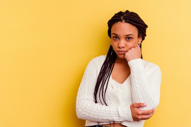 Junge Afroamerikanerfrau lokalisiert auf gelber Wand, die sich traurig und nachdenklich fühlt und Kopierraum betrachtet.