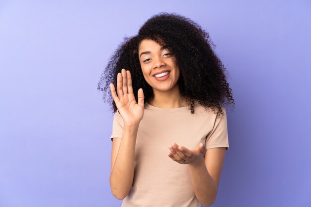 Junge Afroamerikanerfrau lokalisiert auf lila applaudierend nach Präsentation in einer Konferenz