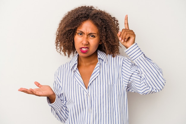 Junge Afroamerikanerfrau mit dem lockigen Haar lokalisiert auf weißem Hintergrund, der ein Produkt auf der Hand hält und zeigt.