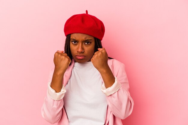 Junge Afroamerikanerin einzeln auf rosafarbenem Hintergrund, die einen Schlag wirft, Wut, Kämpfe aufgrund eines Streits, Boxen.