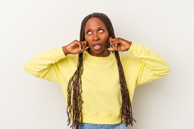 Junge Afroamerikanerin isoliert auf weißem Hintergrund, die Ohren mit den Fingern bedeckt, gestresst und verzweifelt durch eine laute Umgebung.