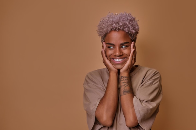 Junge Afroamerikanerin lächelt schüchtern mit verträumtem Gesichtsausdruck