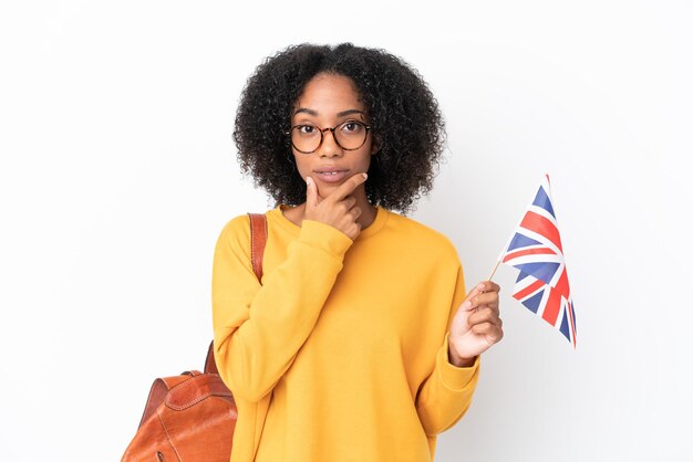 Junge Afroamerikanerin mit einer Flagge des Vereinigten Königreichs isoliert auf weißem Hintergrund denken