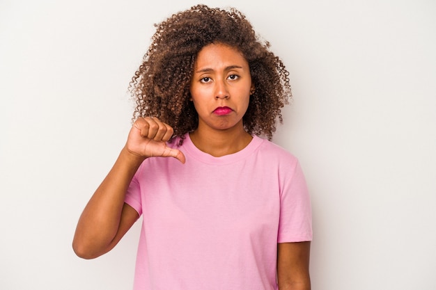 Junge Afroamerikanerin mit lockigem Haar isoliert auf weißem Hintergrund, die eine Abneigungsgeste zeigt, Daumen nach unten. Meinungsverschiedenheit Konzept.