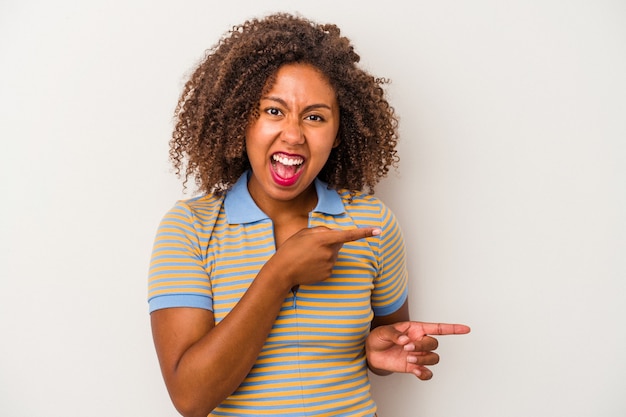 Junge Afroamerikanerin mit lockigem Haar isoliert auf weißem Hintergrund, die mit den Zeigefingern auf einen Kopienraum zeigt und Aufregung und Verlangen ausdrückt.