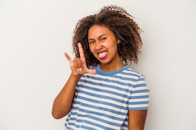 Junge Afroamerikanerin mit lockigem Haar isoliert auf weißem Hintergrund, die Rockgeste mit den Fingern zeigt