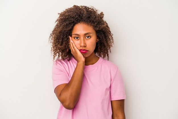 Junge Afroamerikanerin mit lockigem Haar isoliert auf weißem Hintergrund, die sich traurig und nachdenklich fühlt und Kopienraum betrachtet.