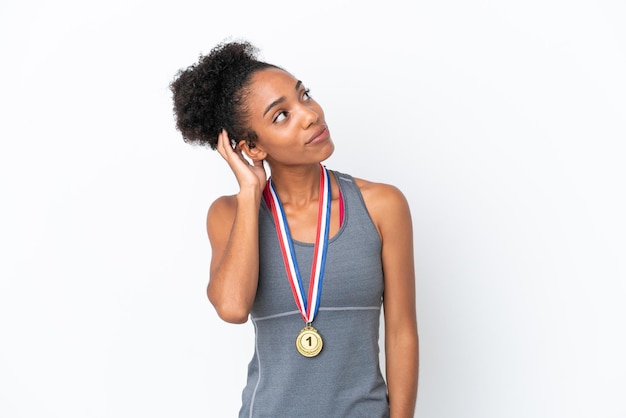 Junge Afroamerikanerin mit Medaillen isoliert auf weißem Hintergrund denkt an eine Idee