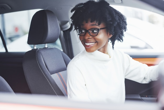 Junge Afroamerikanerin sitzt im neuen modernen Auto.