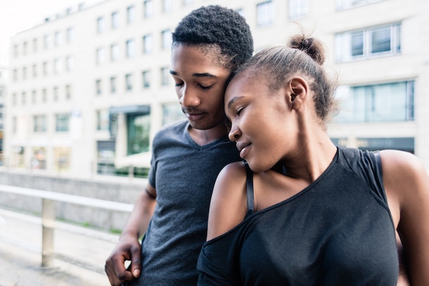 Junge Afroamerikanerpaare in der Liebe, die draußen nebeneinander in der Stadt steht