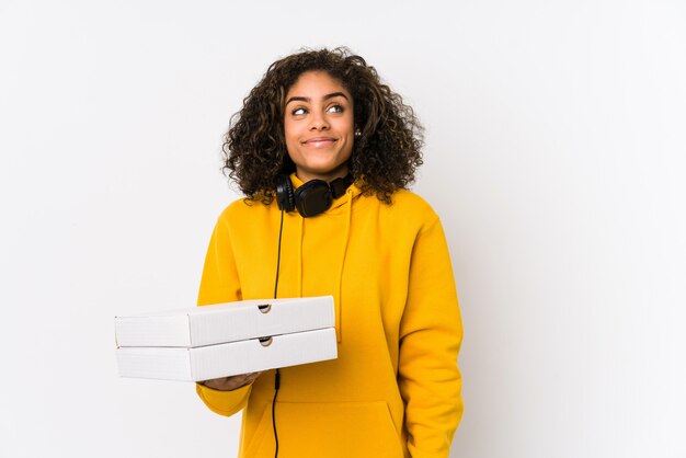 Junge Afroamerikanerstudentenfrau, welche die Pizzas träumen vom Erreichen von Zielen und von Zwecken hält