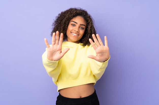 Junge afroamerikanische Frau an der Wand, die zehn mit den Fingern zählt
