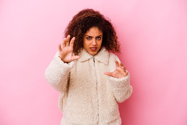 Junge afroamerikanische Frau, die auf rosafarbenem Hintergrund isoliert ist, schreit mit angespannten Händen.