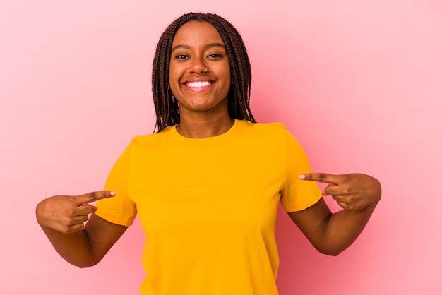 Junge afroamerikanische Frau, die auf rosafarbenem Hintergrund isoliert ist, zeigt mit den Fingern nach unten, positives Gefühl.