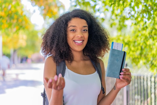 Junge afroamerikanische Frau im Freien mit einem Pass und einer kommenden Geste