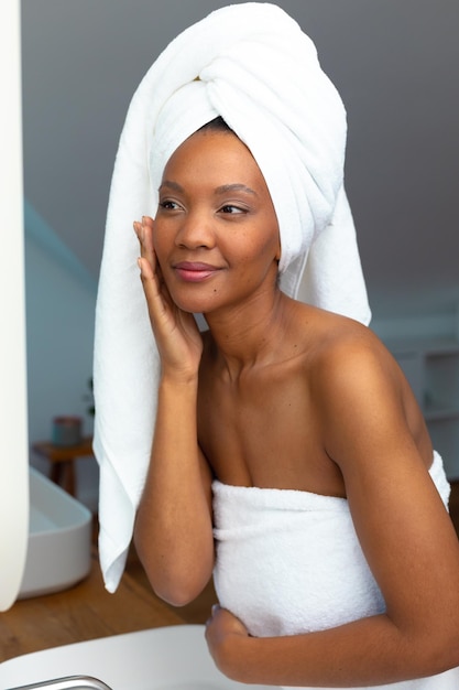Junge afroamerikanische Frau, in ein Handtuch gehüllt, fühlt sich im Badezimmer sicher in ihrer Haut, Kopierraum