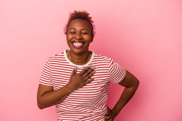 Junge afroamerikanische Frau isoliert auf rosa Hintergrund lachend die Hände auf dem Herzen haltend, Konzept des Glücks.