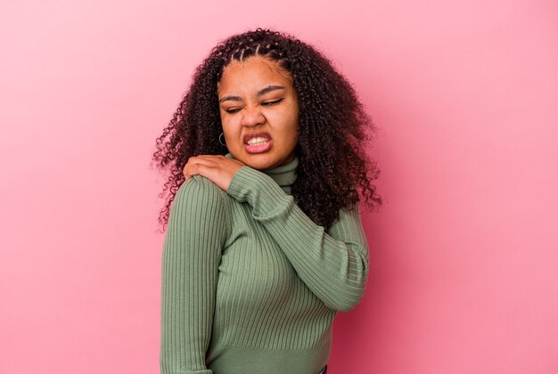 Junge afroamerikanische Frau isoliert auf rosa Hintergrund mit Schulterschmerzen.