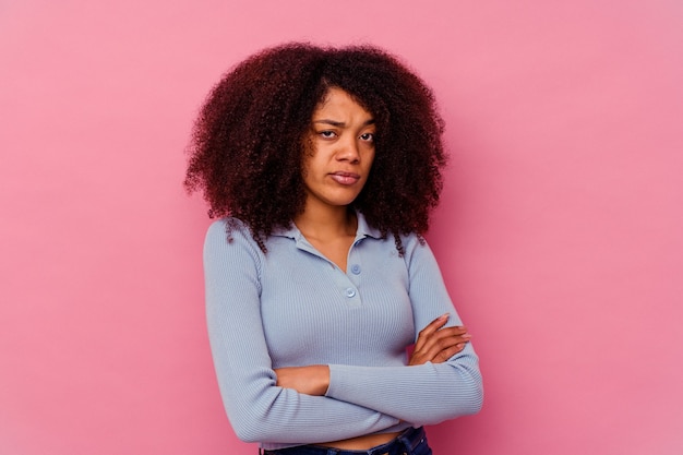 Junge afroamerikanische Frau isoliert auf rosa unglücklich aussehend mit sarkastischem Ausdruck.