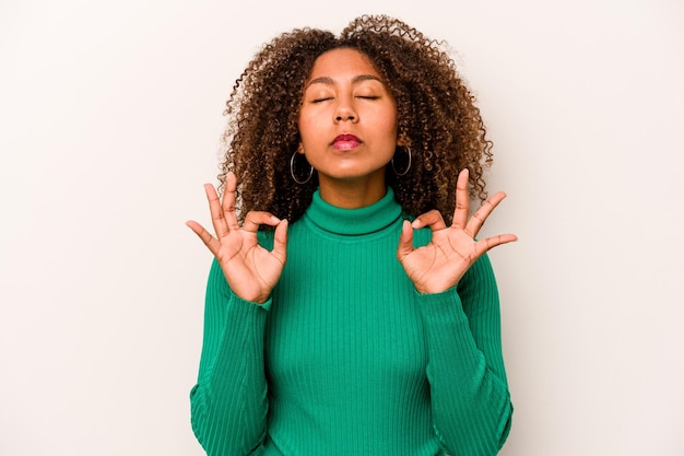 Junge afroamerikanische Frau isoliert auf weißem Hintergrund entspannt sich nach einem harten Arbeitstag, an dem sie Yoga durchführt