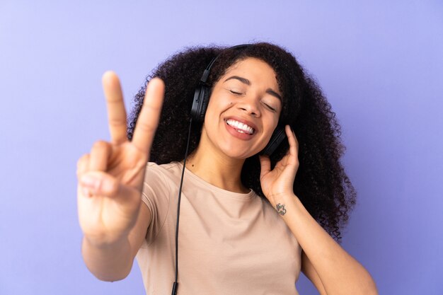 Junge afroamerikanische Frau isoliert hörende Musik und Gesang