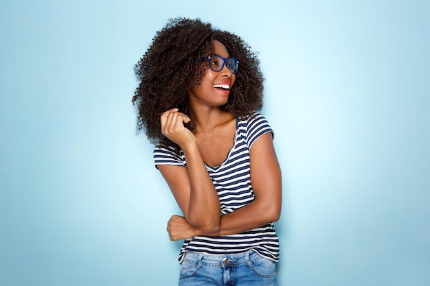 Junge afroamerikanische Frau lächelt mit Brille auf blauem Hintergrund