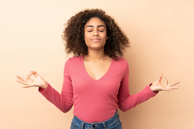 Junge afroamerikanische Frau lokalisiert auf Beige in Zen-Pose