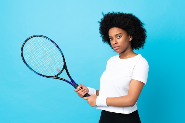 Junge afroamerikanische Frau lokalisiert auf blau spielendem Tennis