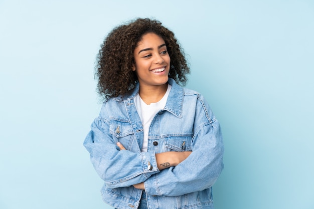 Junge afroamerikanische Frau lokalisiert auf blauem Raum glücklich und lächelnd
