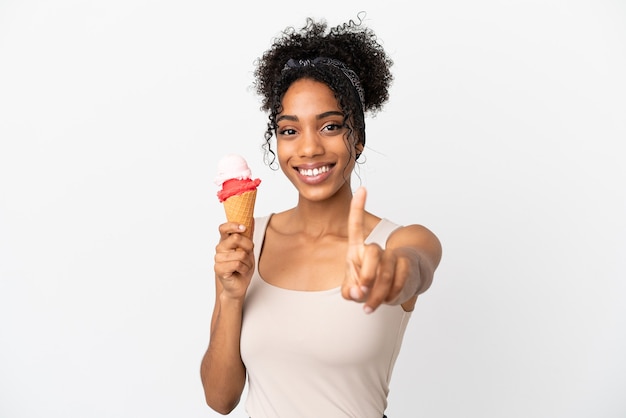 Junge afroamerikanische Frau mit einem Kornett-Eis isoliert auf weißem Hintergrund, der einen Finger zeigt und hebt