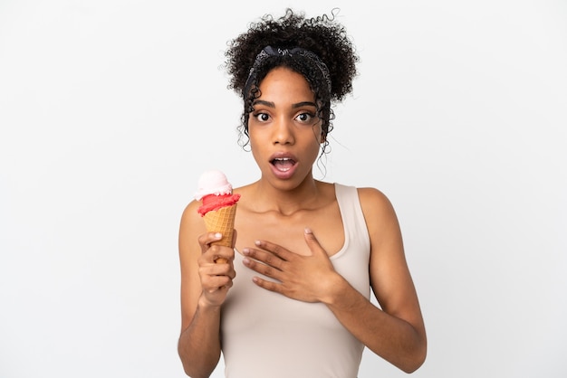 Junge afroamerikanische Frau mit einem Kornett-Eis isoliert auf weißem Hintergrund überrascht und schockiert, während sie nach rechts schaut