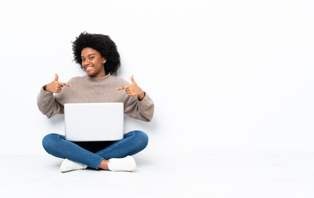 Junge afroamerikanische frau mit einem laptop, der auf dem boden stolz und selbstzufrieden sitzt